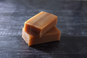 Two pieces of natural laundry soap on a dark surface