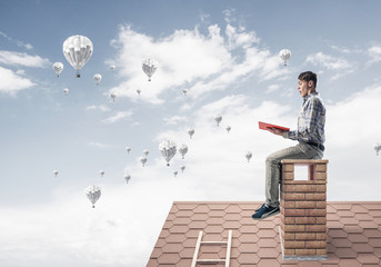 Handsome student guy reading book and aerostats flying in air