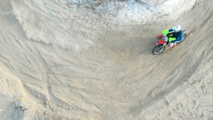 Aerial: Birds eye view of a motocross men riders riding snow track in winter. Winter sports motobike riding. Snow motocross racing aerial video.