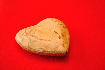 A wooden heart isolated against a red background