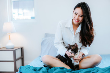 Asian woman playing with cat pet in the morning at holiday hobbie happy lifestyle in bedroom at home