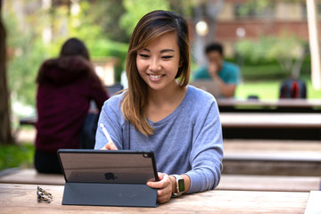 Asian american student on tablet computer with stylus, wireless internet technology