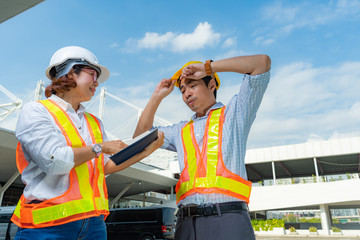 Male and Female Industrial and civil engineers wear personal protective equipment, discuss the end of project and working in project site.partnership agreement, teamwork and business concept,