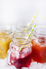 Fototapeta na wymiar Variety of Tasty Juices in Glass Jars Mugs Healthy Beverages Drinks White Background Vertical