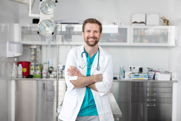 Portrait of smiling doctor standing with arms crossed at veterinary clinic - obrazy, fototapety, plakaty