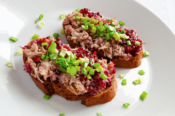 two open sandwiches with rabbit rillette and bog berry jam decorated with chopped green onion