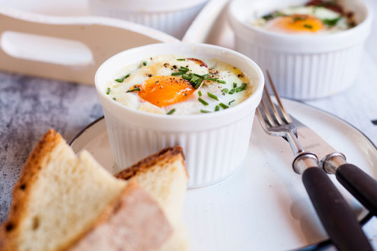 Oeufs en cocotte Individual baked eggs with spinach, feta, bacon, eggs, and slices of bread