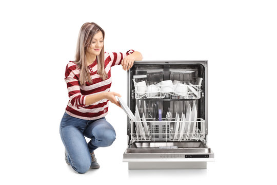 Beautiful young woman putting a plate into a dishwasher