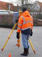 Surveyor, a civil engineer with surveying equipment to prepare a construction site