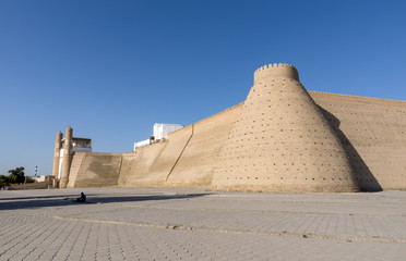 Fototapeta na wymiar Entrance and Wall of the massive Ark fortress, located in the city of Bukhara, Uzbekistan. The Ark is a large earthen fortification located in the northwestern part of contemporary Bukhara