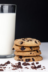 Stack of chocolate chips cookies and milk on black background. Mockup for input the text.
