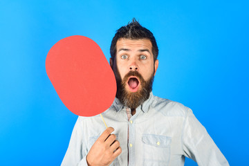 Shocked bearded man with name plate. Attractive bearded guy in white shirt. Fashionable man with short hair in casual wear. Surprised man with opened mouth holds nameplate. Feelings&Emotion