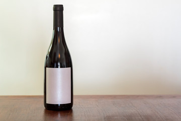 Glass bottle of red wine with label on table against white background