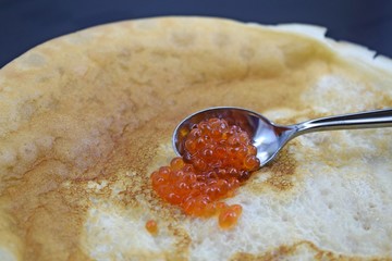 Delicious fresh pancakes and red caviar in a spoon.