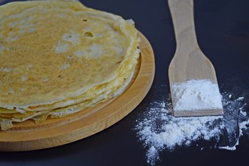 Delicious pancakes and flour on black background.