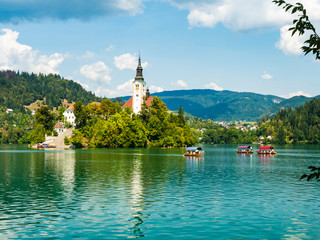 Lake Bled with its island, in Slovenia Europe, in summer, tourists on boats on a beautiful day with...