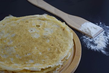 Delicious pancakes and flour on black background.
