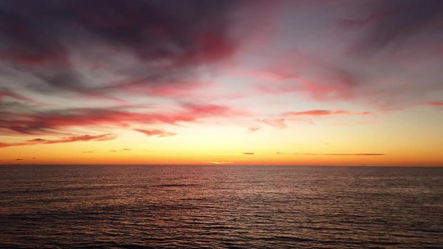 Sunset over  sea in golden hour with pastel colored orange and pink sky and wavy water surface and bright horizon