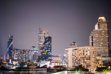 Colorful Abstract Photo blurred of city modern buildings night bangkok cityscape view at twilight time, Decorated with de-focus bokeh cities offices of reflecting building in Bangkok Thailand.