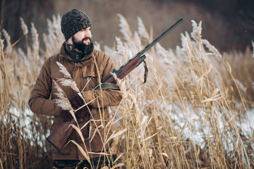 happy cheerful hunter holding a rifle and looking aside. close up photo. copy space