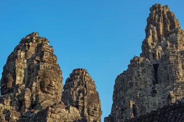 Fototapeta na wymiar Faces of ancient Bayon Temple at Siem Reap in Cambodia with blue color background from the sky.