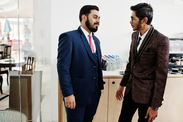 Two indian businessman in suits standing on cafe and discuss each other.