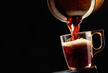 Small cup of coffee on a black background.