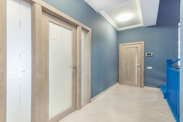 Fototapeta na wymiar Bright hallway with laminate flooring, high ceiling, front door and modern glass door .to living room