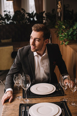 handsome man in suit waiting for girlfriend in restaurant