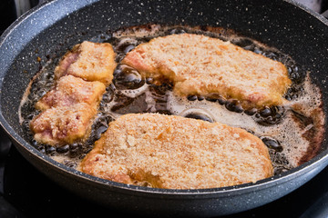 Preparing schnitzel on frying pan