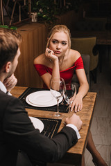 bored attractive girlfriend looking at boyfriend in suit