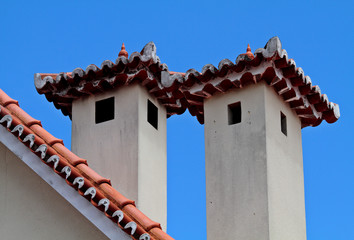 Two chimneys over a rooftop against the sky