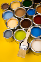 Paint can with a paintbrush, yellow background