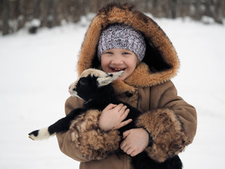 Happy little girl with a newborn lamb in her arms