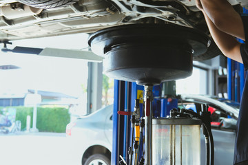 vehicle lift up by hydraulic for motor oil change & transmission inspection. changing  engine oil in automobile repair service. maintenance & checkup in car workshop.