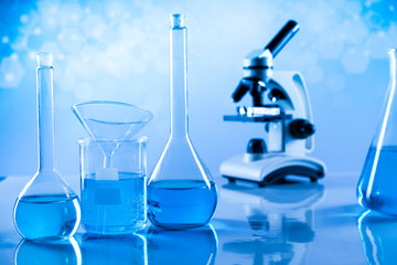 Laboratory beakers, microscope, blue background