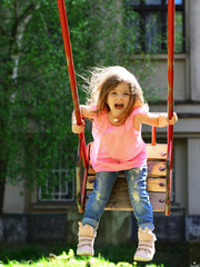 Playground in park. Small kid playing in summer. Happy laughing child girl on swing. romantic little girl on the swing, sweet dreams. childhood daydream .teen freedom. Active day