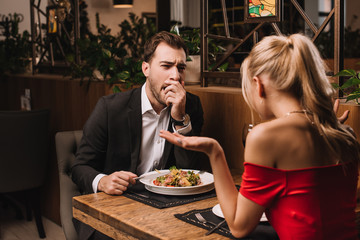 man yawning while listening girlfriend in restaurant