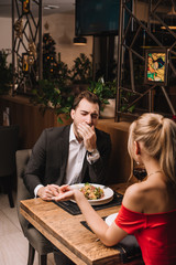 boyfriend yawning while listening girl in restaurant