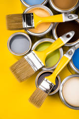 Tin cans with paint and brushes, yellow background