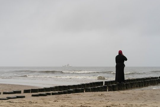 freau mit rotem kopftuch auf einer bune am strand von ahlbeck auf usedom