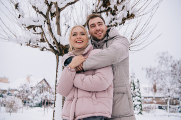 happy man and woman embrace each other in daytime in winter