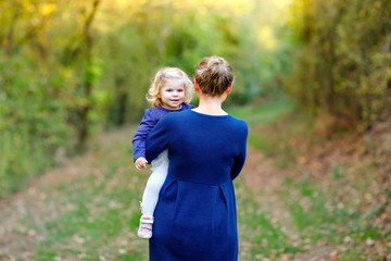 Happy young mother having fun cute toddler daughter, family portrait together. Woman with beautiful baby girl in nature and forest. Mum with little child outdoors, hugging. Love, bonding.