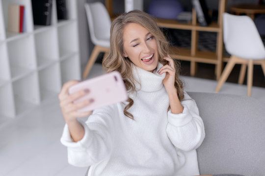 Beautiful happy girl taking pictures of herself on a mobile phone. Selfie photo.
