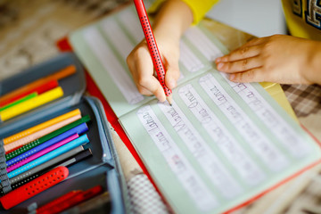 lose-up of little kid boy at home making homework, child writing first letters and words like mama...