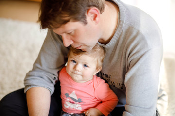 Happy proud young father having fun with baby daughter, family portrait together. Dad with baby girl, love. Man playing with little child at home.