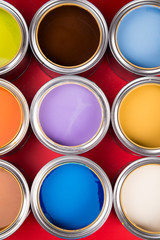 Collection of colored paints cans, red background