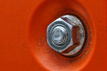 Obraz premium gray iron nut on a bolt on a dirty orange plastic wall