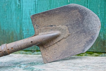 old gray dirty iron shovel on a wooden board
