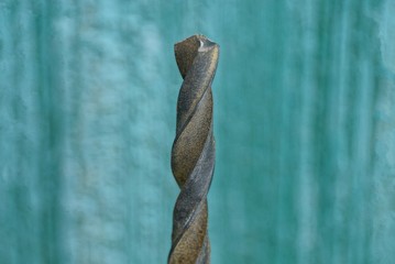 gray steel drill against a green wall
